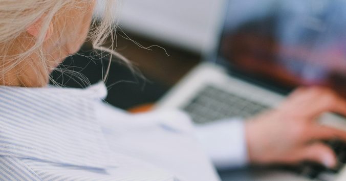 Older lady with light hair and a pinstriped shirt sitting in front of a laptop. Photo by Shvets from Pexels.