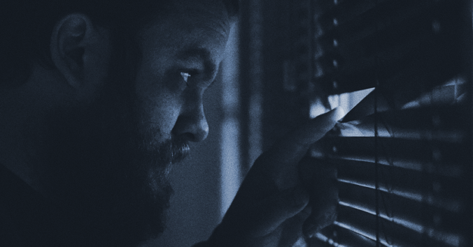 man looking through blinds